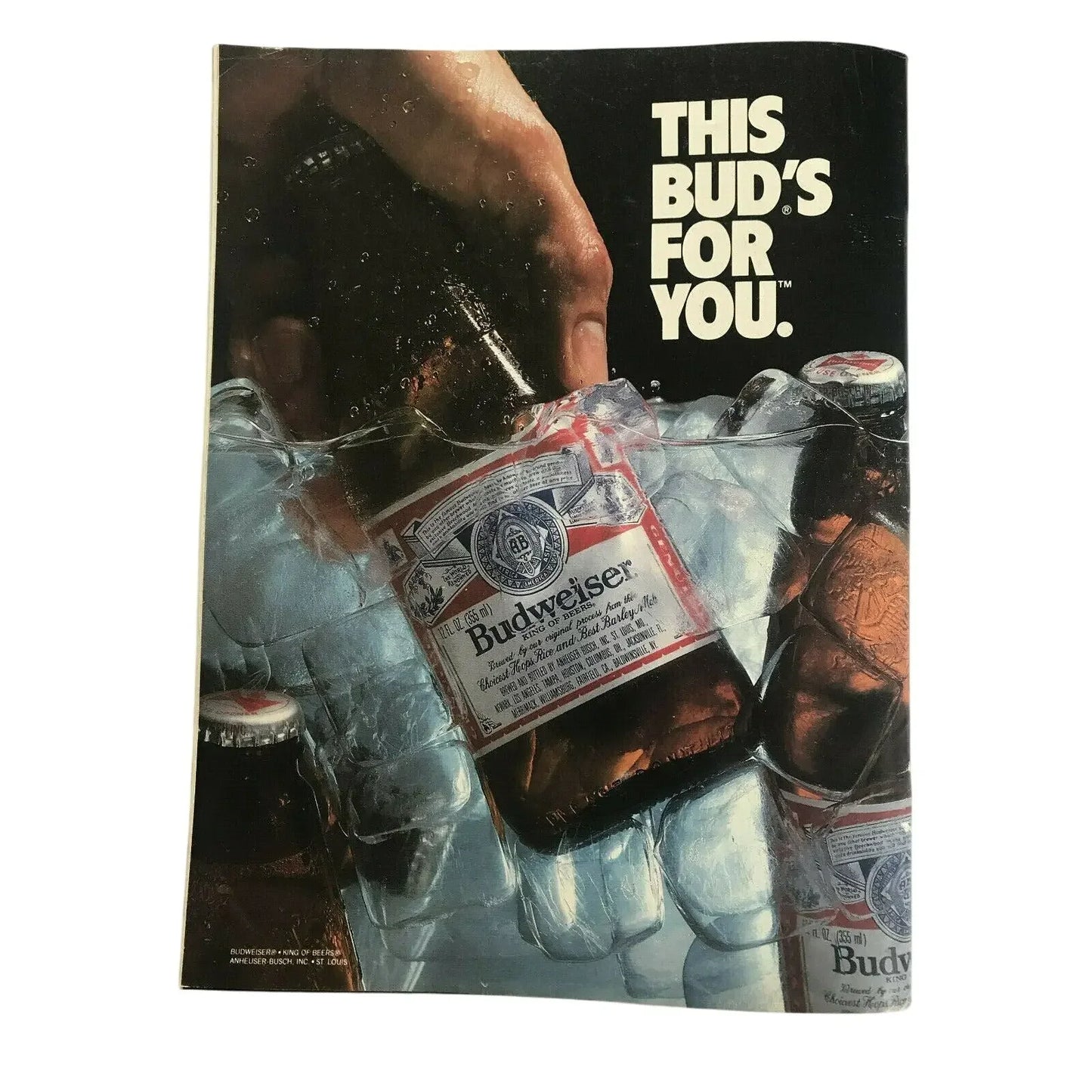 Hand grabbing Budweiser beer bottle from ice with 'This Bud's for you' text in background
