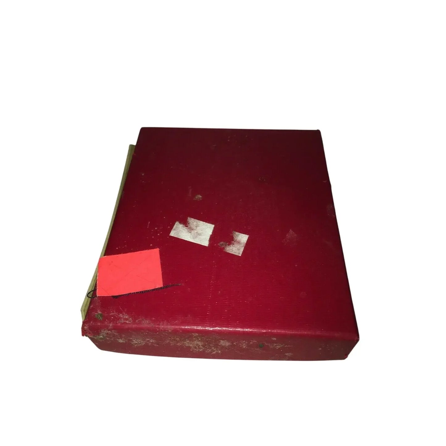 Worn red cardboard box with white marks and a small red paper label on top