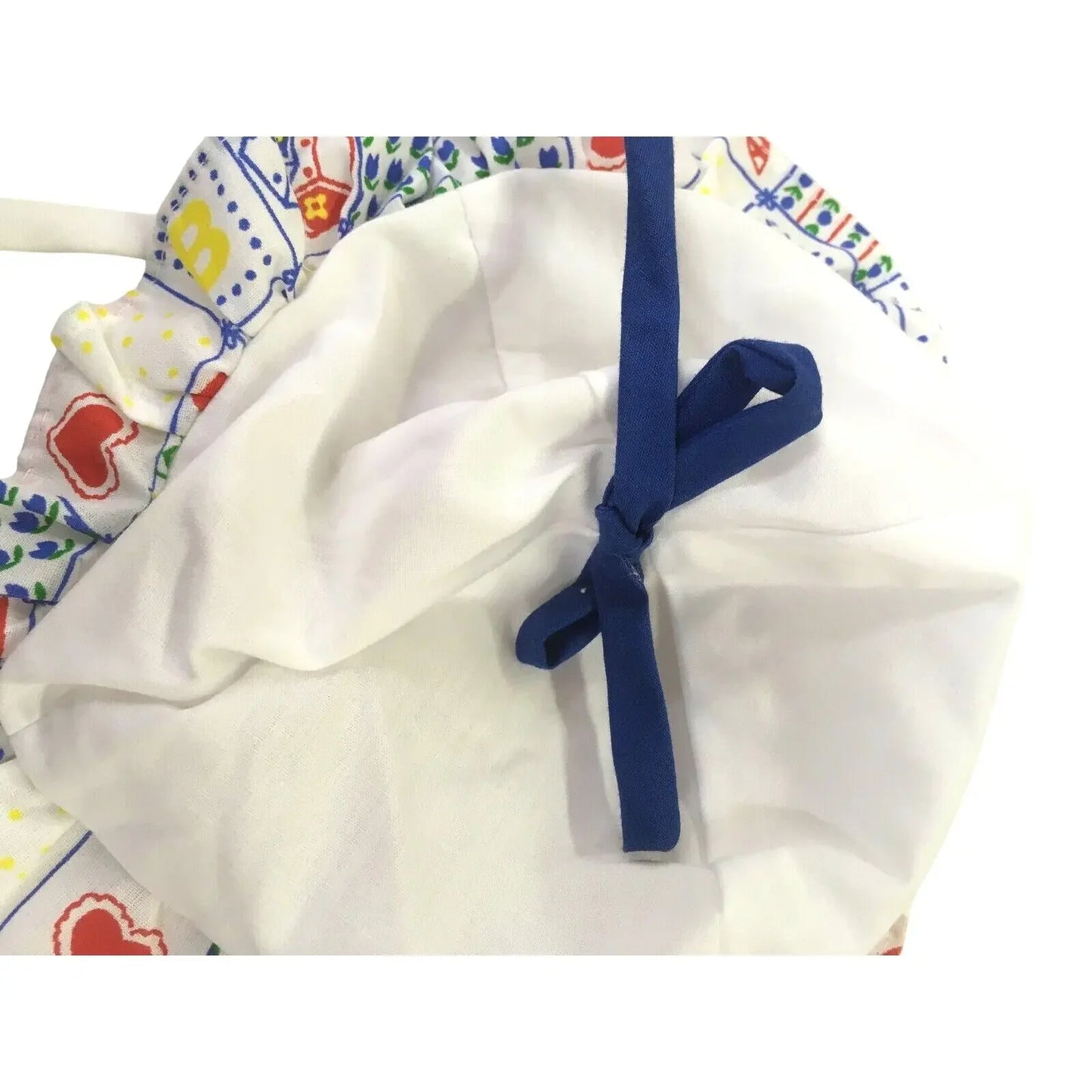 White fabric bonnet with colorful patterned trim and blue ribbon tie