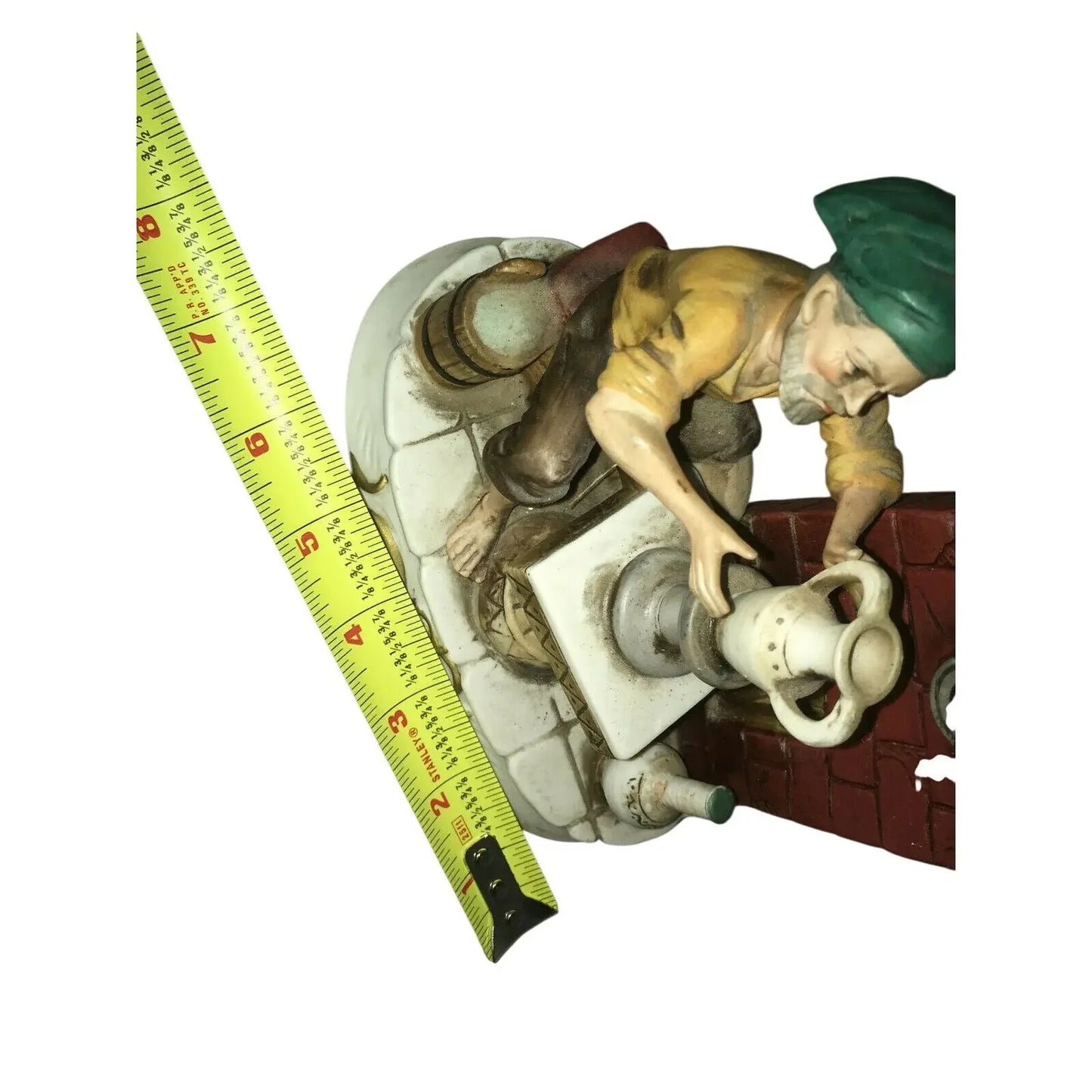 Vintage figurine of man turning valve with measuring tape for size reference