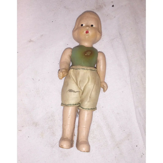 Vintage doll with short blond hair, green top, and beige shorts on a white background