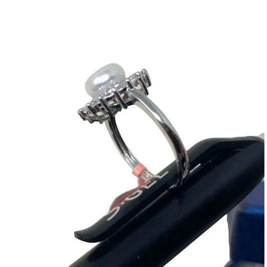 Silver ring with round white pearl and clear gemstones on white background