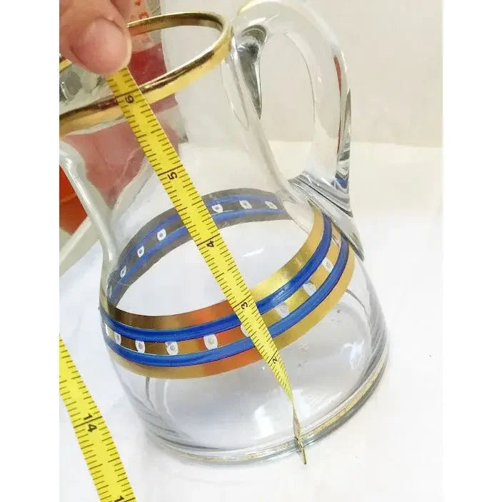 Clear glass pitcher with gold and blue bands being measured with a yellow tape measure
