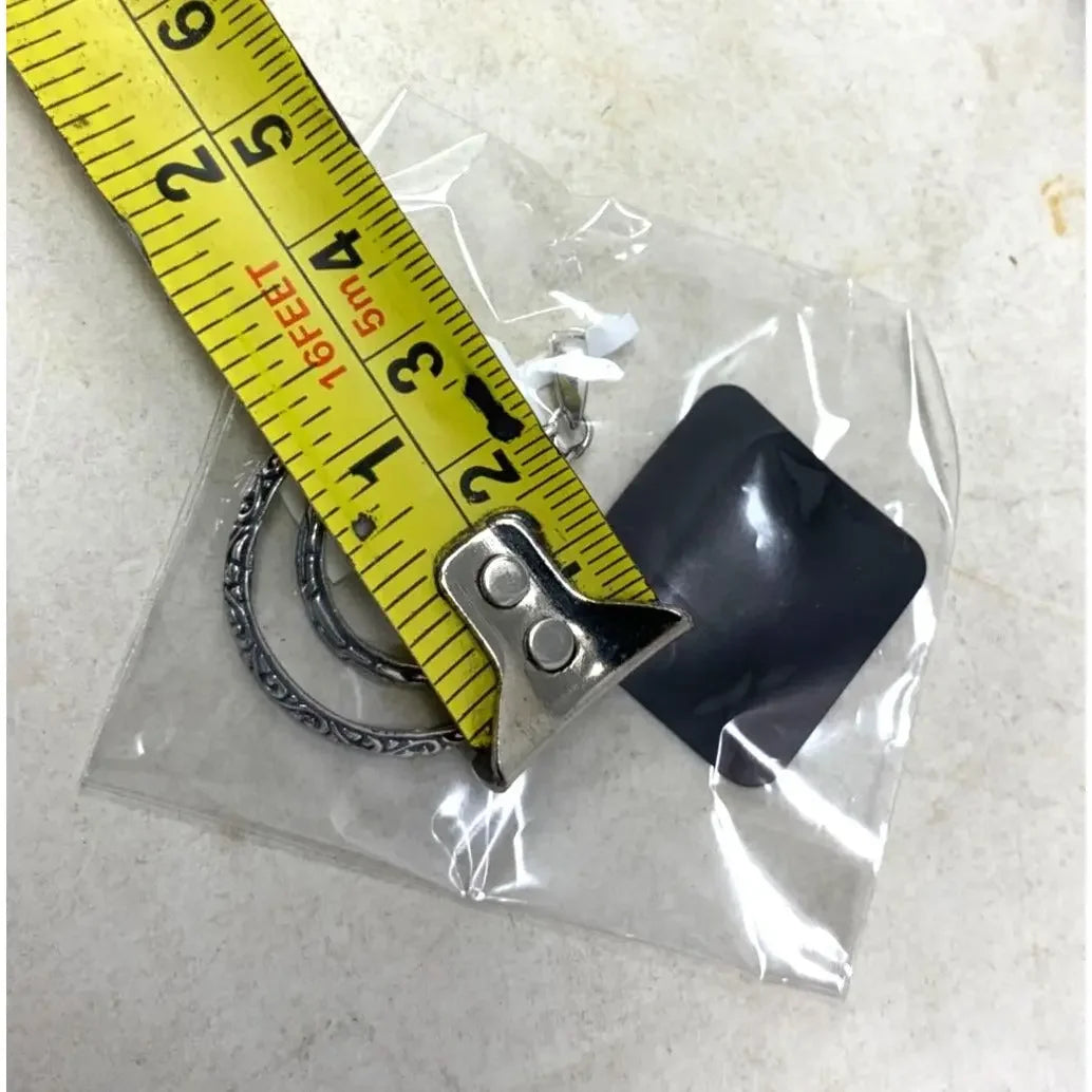 Silver keyrings in plastic bag measured with yellow tape measure on white surface