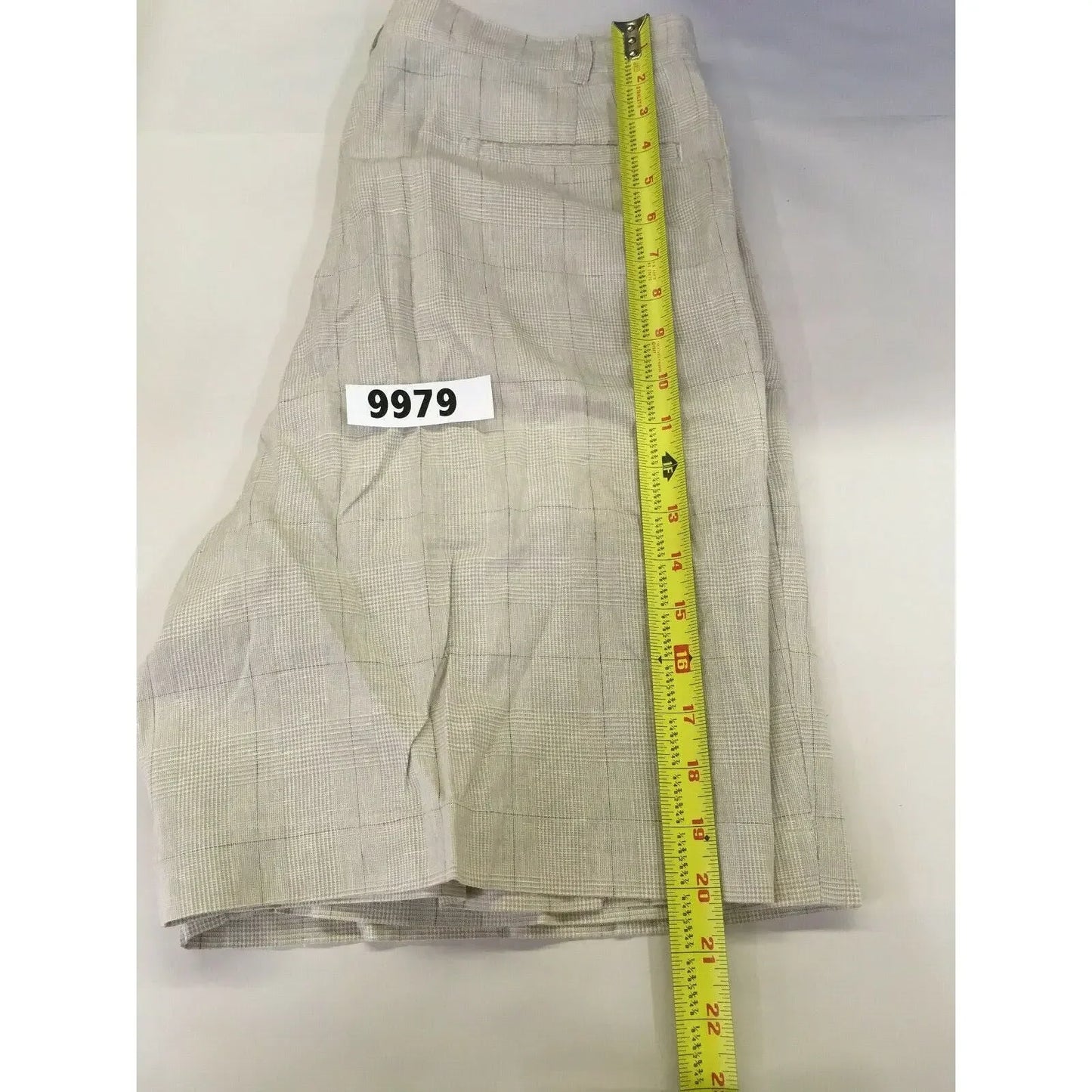 Beige plaid shorts measured with tape, tag number 9979, on white background