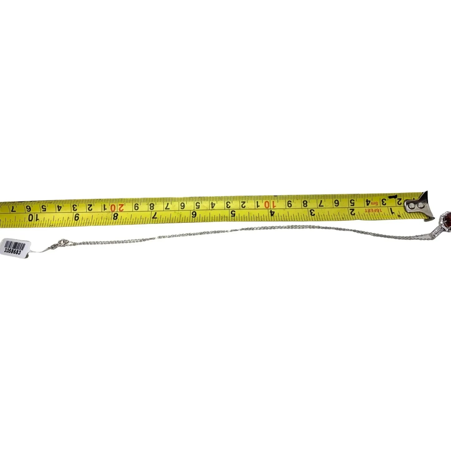 Silver chain necklace with clasp next to yellow measuring tape on white background