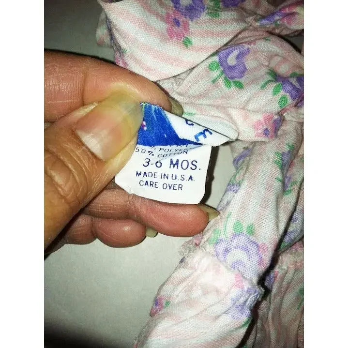 Hand holding floral baby clothing with size tag reading 3-6 months, made in USA.