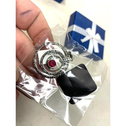 Silver spiral keychain with red gemstone center in plastic bag, blue gift box background