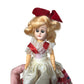 Vintage Collectible Doll With Blonde Hair wearing floral printed dress/red bow