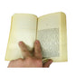 Hand holding open paperback book, showing inside pages with visible text.