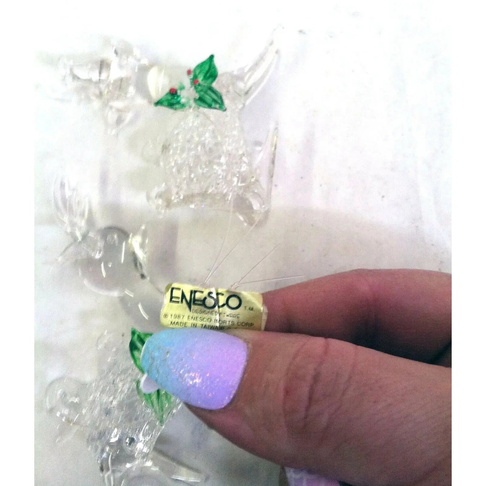 Hand holding vintage clear glass reindeer ornament with green leaf accents and Enesco label