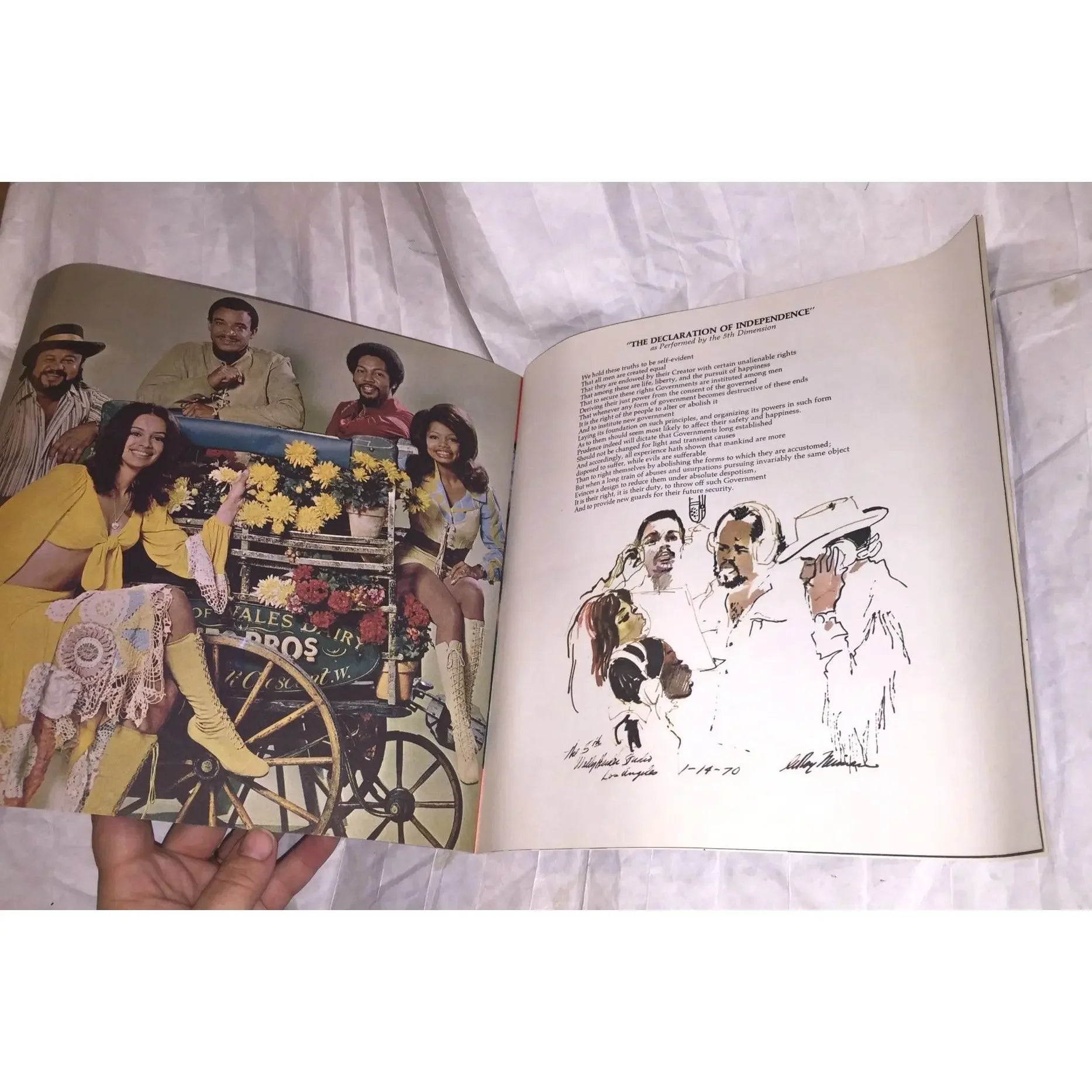 Open vintage book showing a color photo of people in retro clothing and an illustrated Declaration of Independence page.