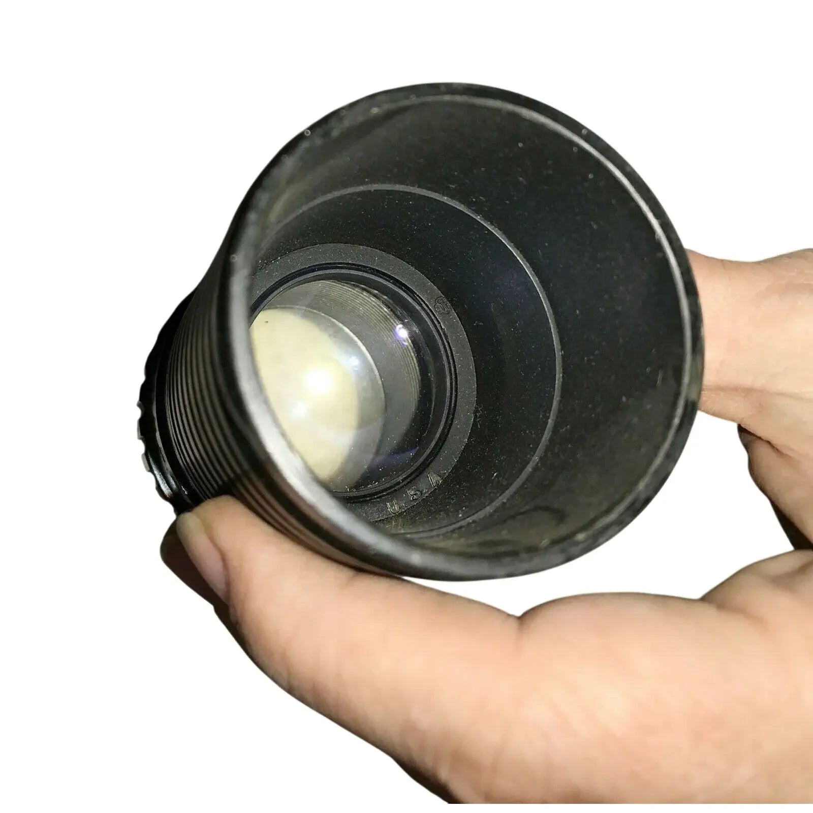Hand holding a black camera lens with visible glass elements on white background