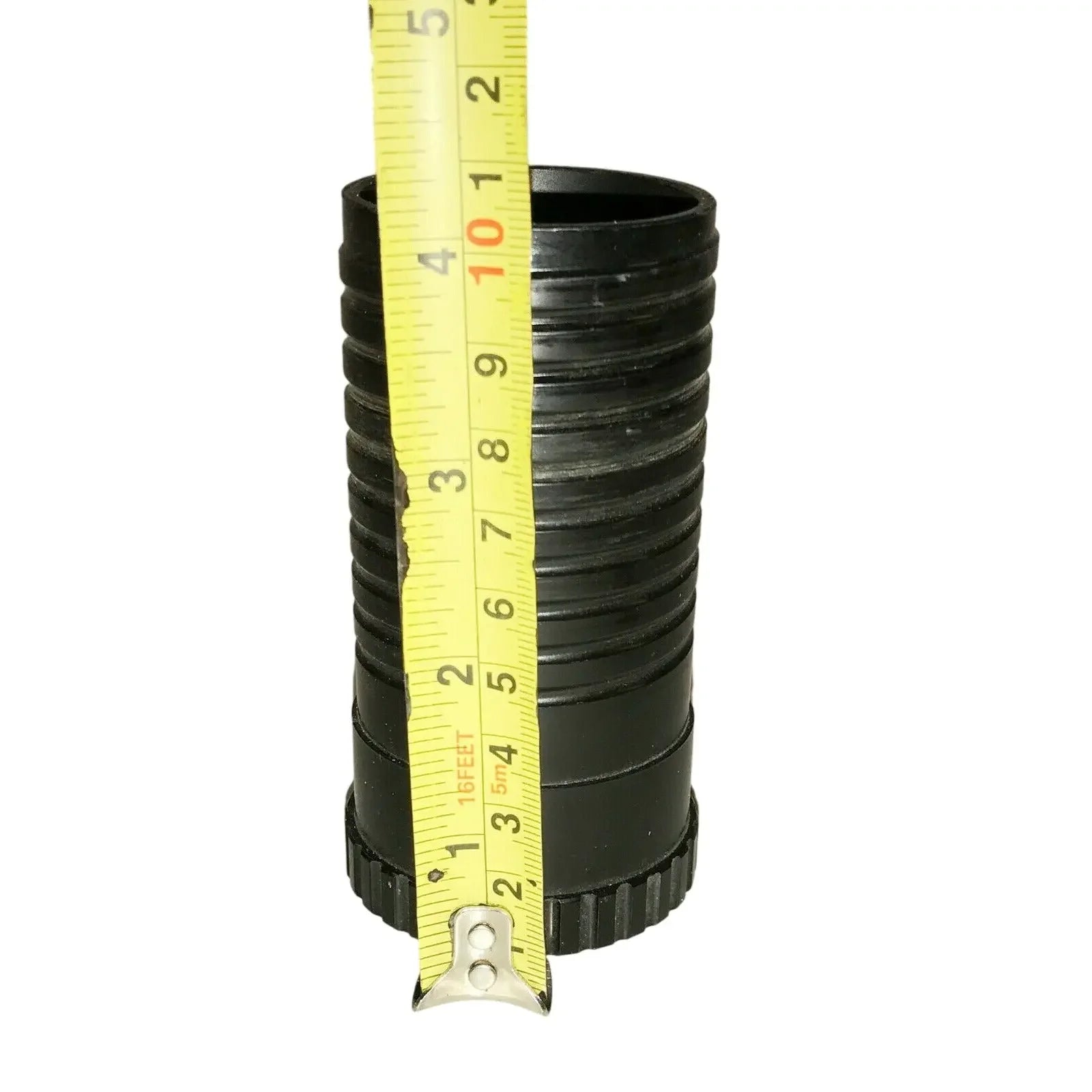 Black ribbed pipe fitting measured with a yellow tape measure, plumbing accessory