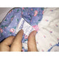 Close-up of floral fabric dress tag with care instructions held by hand