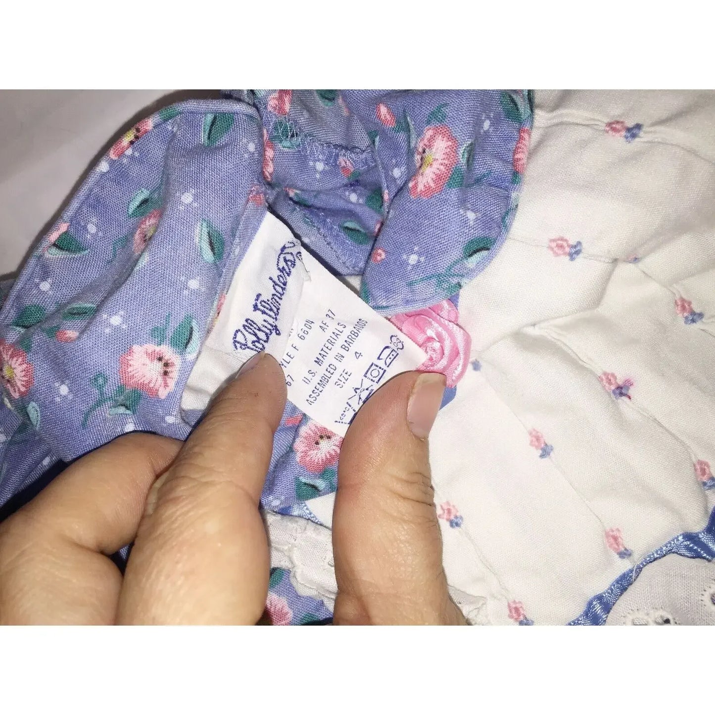 Close-up of floral fabric dress tag with care instructions held by hand
