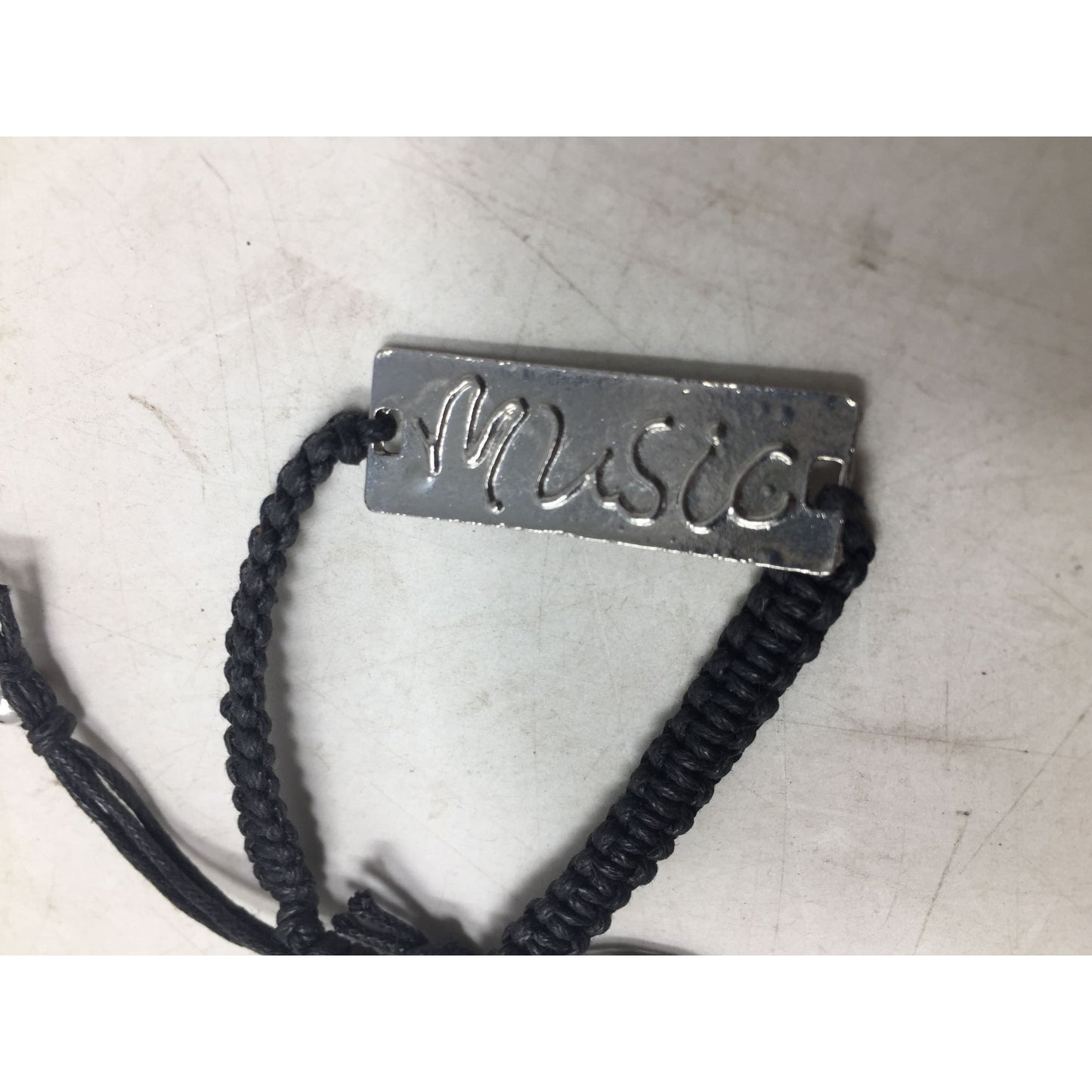 Black Bracelet with Silver Tone Pendant that says ''Music'' in Cursive