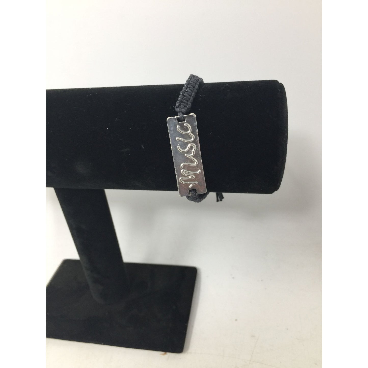 Black Bracelet with Silver Tone Pendant that says ''Music'' in Cursive
