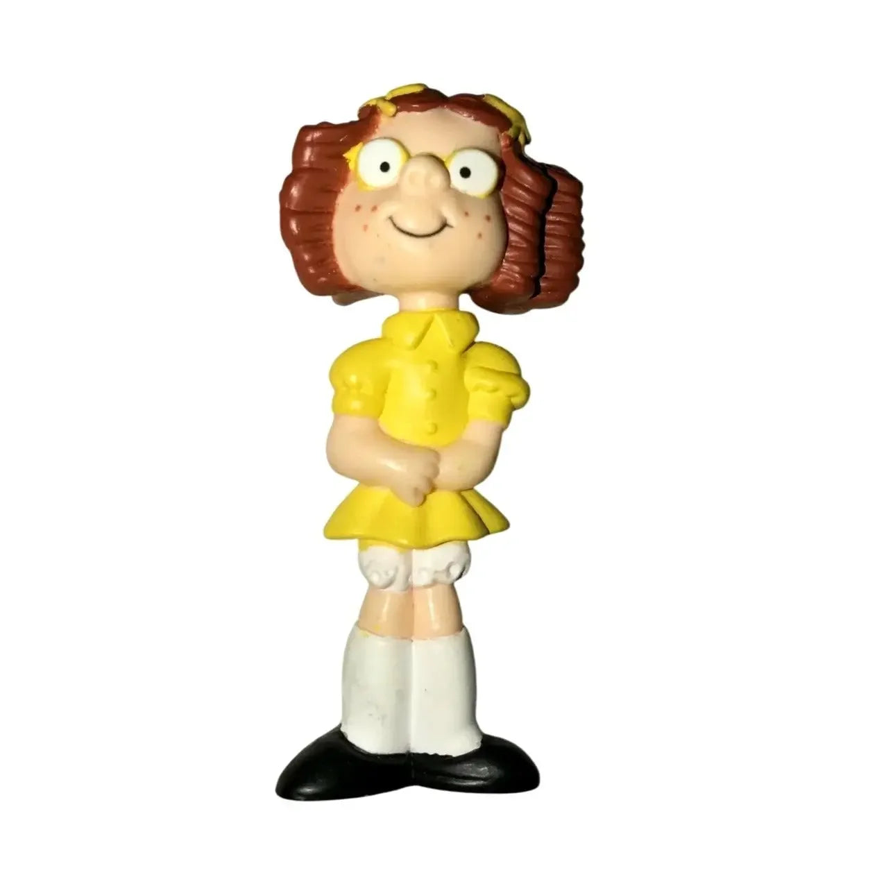 Cartoon girl toy figurine with brown hair, yellow dress, and white socks on white background