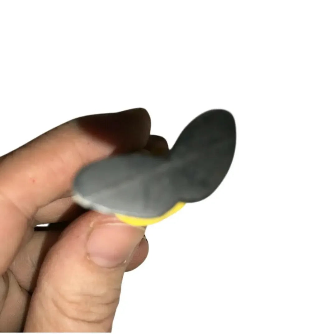 Hand holding a small grey and yellow object with a rounded, flat shape on white background