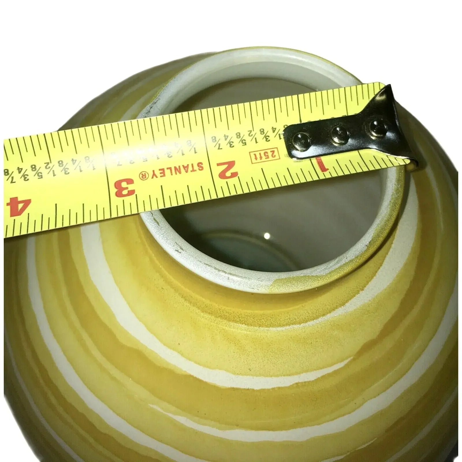 Yellow striped ceramic vase with tape measure showing opening diameter