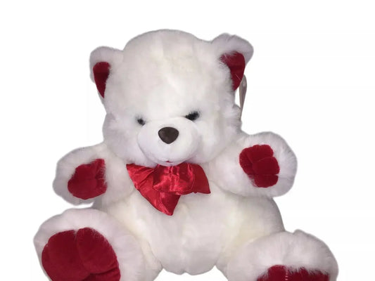 White teddy bear plush toy with red ears, red paws, and a red bow tie, isolated on white background
