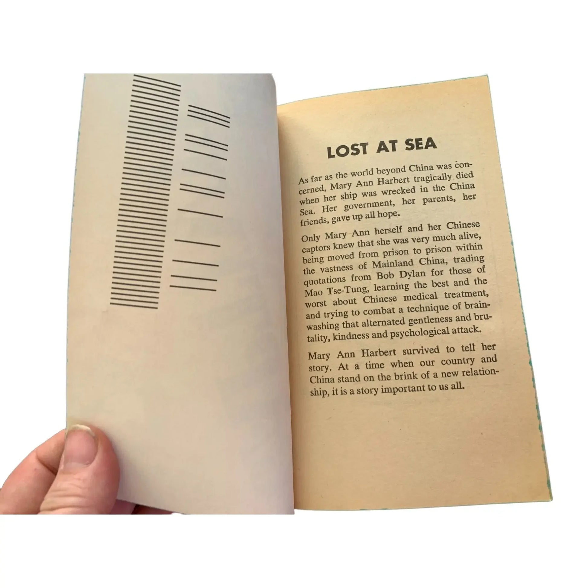 Hand holding open vintage book, showing the 'Lost at Sea' page with printed text.