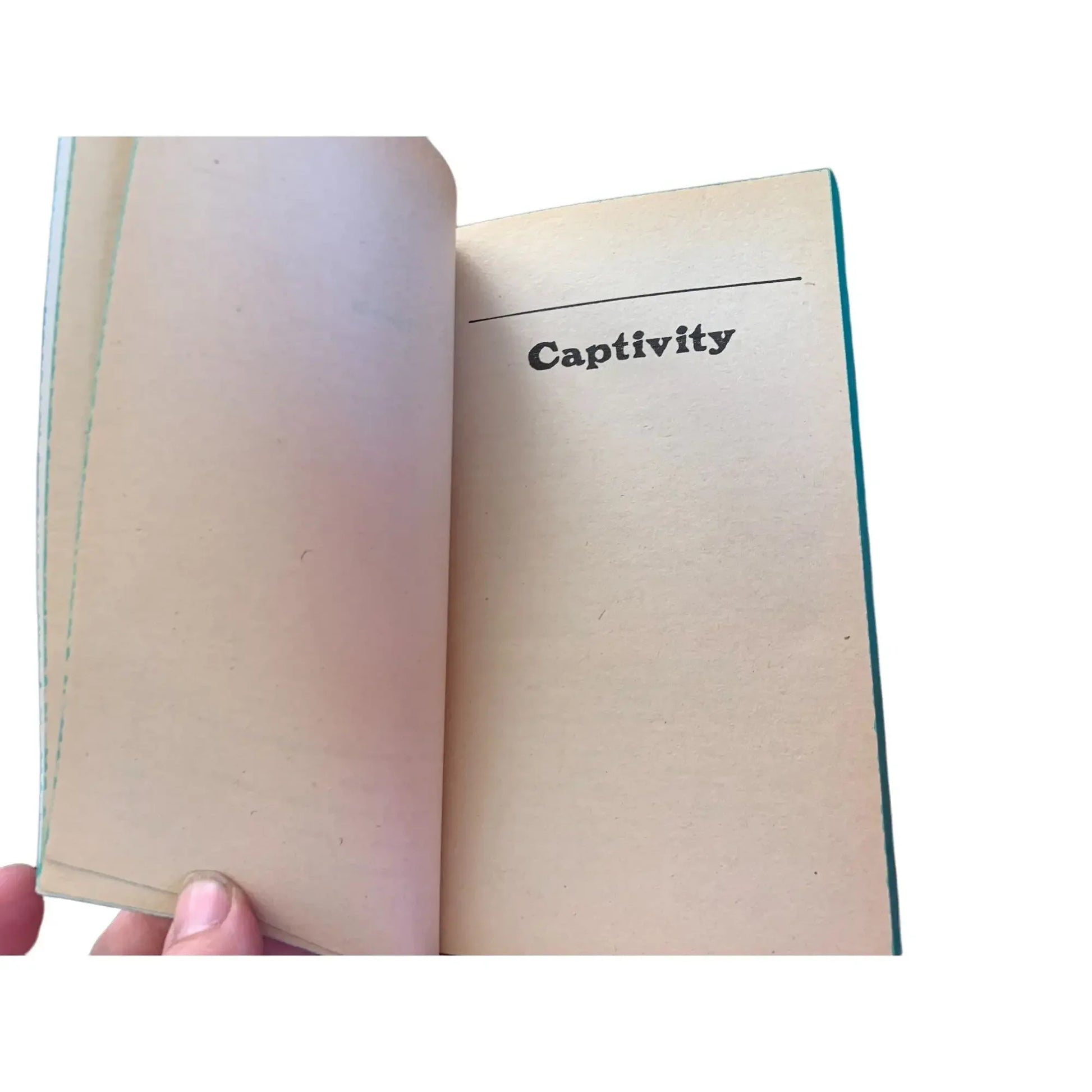 Hand holding open vintage book to chapter titled Captivity on off-white page