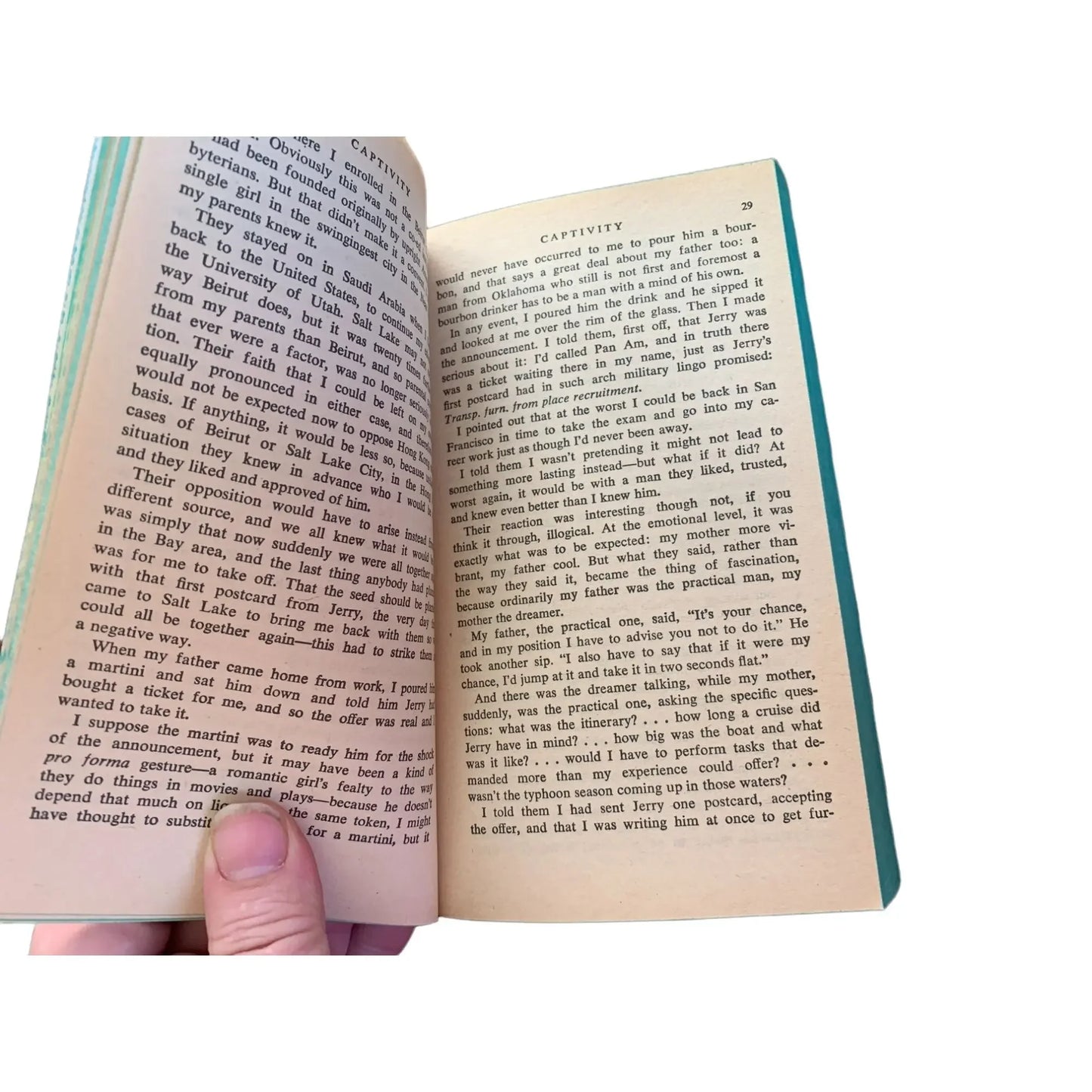 Hand holding open book showing two pages of text against white background
