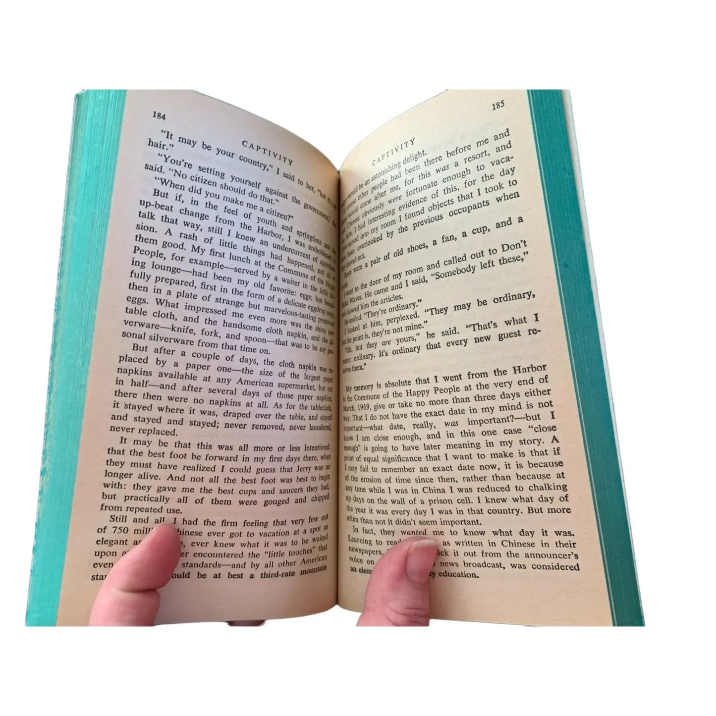 Person holding open a hardcover book, showing two pages with text in English.